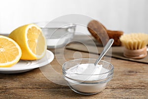 Baking soda in glass bowl on wooden table. Natural detergent