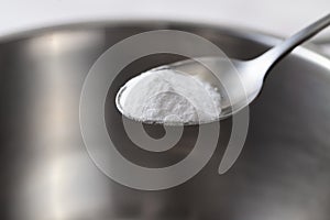 Baking soda in a spoon over a metal dish