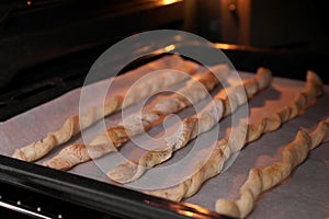 Baking tasty homemade breadsticks in oven, closeup. Cooking grissini