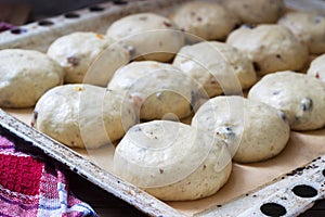 Baking tray with round uncooked cross buns on a wooden table