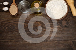 Baking utensils and ingredients for pizza dough on wooden background.
