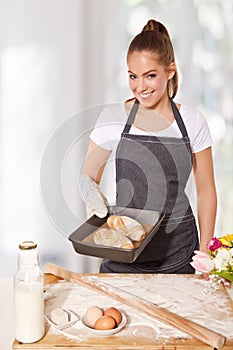 Baking woman showing a tray of fresh bread roll (made of rye flour)