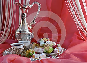 Baklava oriental sweets on a tray with cups of tea, coffee or red wine with a silver shiny jug