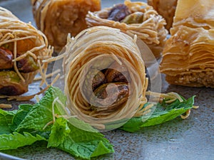 Baklava rolls with whole pistachios on menthe leafs, head on shot, close up