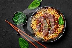 Bakmi or Mie Ayam in black bowl on dark slate table top. Indonesian cuisine noodles meat dish. Traditional asian food