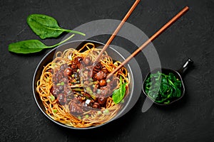 Bakmi or Mie Ayam in black bowl on dark slate table top. Indonesian cuisine noodles meat dish. Traditional asian food