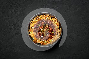 Bakmi or Mie Ayam in black bowl on dark slate table top. Indonesian cuisine noodles meat dish. Traditional asian food