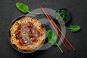 Bakmi or Mie Ayam in black bowl on dark slate table top. Indonesian cuisine noodles meat dish. Traditional asian food