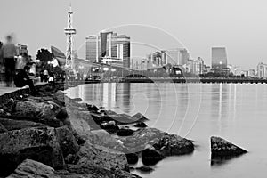 Baku Bulvar from shore at night with lights and boy looking out to sea, in black and white