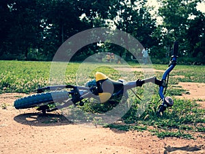 Balance bike lying on the grass in the summer park. Falling off a bike on a sunny day