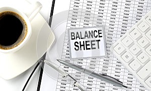 BALANCE SHEET text on sticky on the chart with coffee,pen and calculator