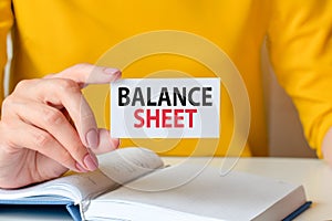 balance sheet written on a paper card in woman hand, concept