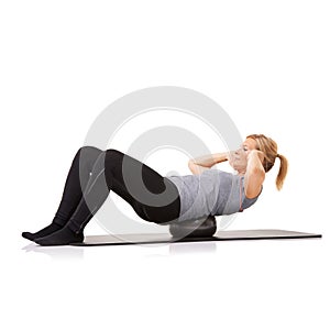 Balance and sit-ups. A young woman doing sit-ups on an exercise ball while isolated on a white background.