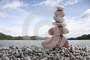 Balance stone on pile rock with river background.