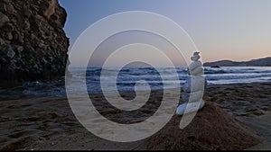 Balance stones on beach at sunset. Rock and sea waves in background. Concept of zen, relax, meditation, fragility