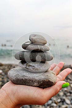 Balance of stones on the hand against the background of the sea.