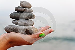 Balance of stones on the hand against the background of the sea.