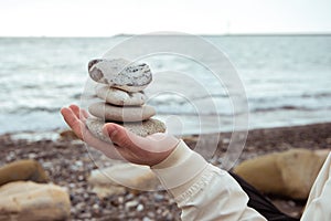 Balance of stones on the hand against the background of the sea. The concept of peace of mind, harmony, spirituality