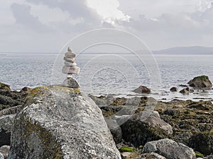 Balance stones on a rock with ocean and cloudy background. Concept hard work, goal achievement, insistence, tenacity