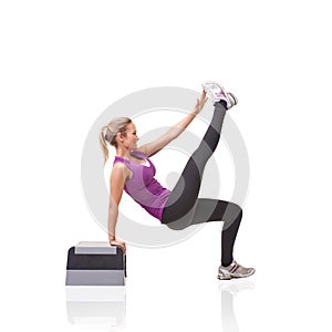 Balance and tone. A smiling young woman doing aerobics on an aerobic step isolated against a white background.