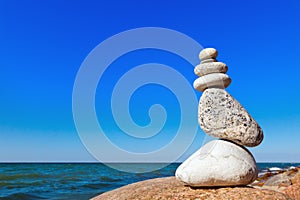 Balance of white stones on a background of blue sky and sea