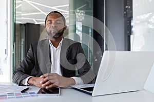 Balanced and calm man at workplace inside office, businessman meditating with closed eyes thinking and visualizing