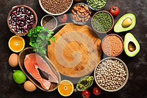 Balanced diet food on a dark background. Healthy eating concept. Empty wooden board and frame of various organic products. Top