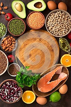 Balanced diet food on a dark background. Healthy eating concept. Empty wooden board and frame of various organic products. Top