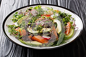 Balanced dietary salad of red fish, avocado, radish and a mix of micro green close-up on the table. horizontal