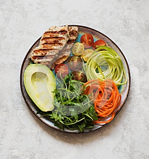 Balanced food concept. Buddha bowl salad with grilled turkey, arugula, avocado, carrots and zucchini, balanced clean eating