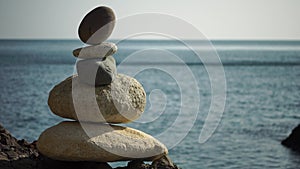 Balanced pebble pyramid on the beach on a sunset time. Sea waves on the background. Selective focus. Zen stones on the