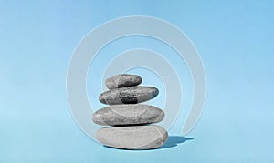 Balanced pebble stones for spa treatments on blue background. The balancing cairn - symbol of harmony, tranquility and