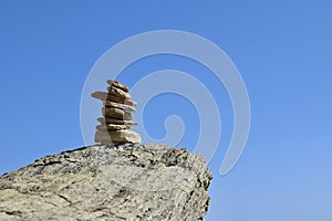 Balanced rock stack against a clear blue sky