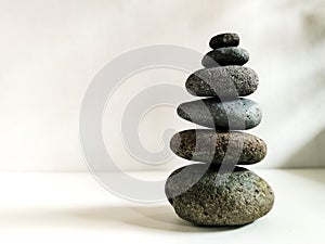 A balanced stack of stones placed one on top of the other against a neutral background.