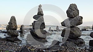 Balanced stones pyramid on beach on sunny day. Against background is not calm sea and waves. Zen stones on sea beach, meditation,