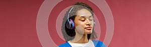 Balanced woman in headphones is meditate hold hands folded in prayer gesture on red background