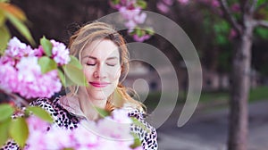 Balanced woman relaxing in park during cherry tree blooming