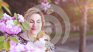 Balanced woman relaxing in sunrays in park during cherry tree blooming