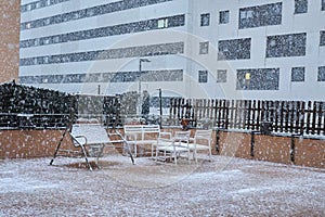 balancin chairs and table snowed by surprise in early spring on the balcony of the house photo