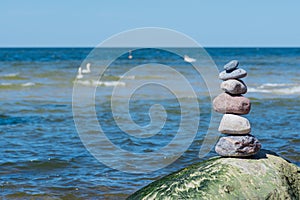 Balancing stones on a big rock with sea grass on the beach