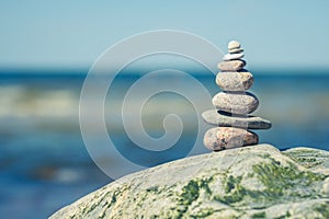 Balancing stones on a big rock with sea grass on the beach