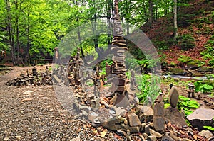 Balancing stones near waterfall Shypit. Stack of stone in summer morning forest. Zakarpattya, Ukraine