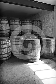 Balck and white old whisky barrels, stacked in a warehouse ready to fill with raw spirit and leave to mature over time, in a dusty