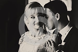 A balck and white picture of smiling bride and groom holding her