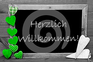 Balckboard With Green Heart Decoration, Text Herzlich Willkommen Means Welcome