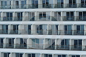 Balconies of passengers cabins in aft part of huge cruise ship of white color moored in port of Caribbean Island.