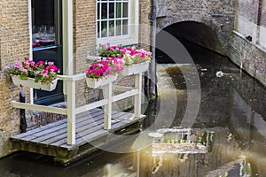 Balcony with colorful flowers at the historic canal of Gouda