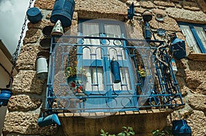 Balcony decorated with lots of blue pans on stone house facade