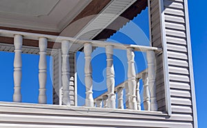 Balcony detail with carved marble balusters - railing and wooden wall cladding.