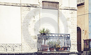 Balcony with flowerpots and house palm plants in a historic building in Acitrezza, Catania, traditional architecture of Sicily,
